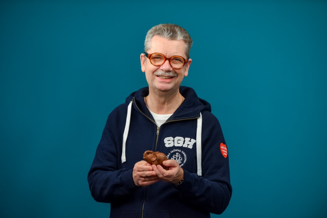 uśmiechnięty rektor w bluzie SGH WOŚP trzyma figurkę słonia