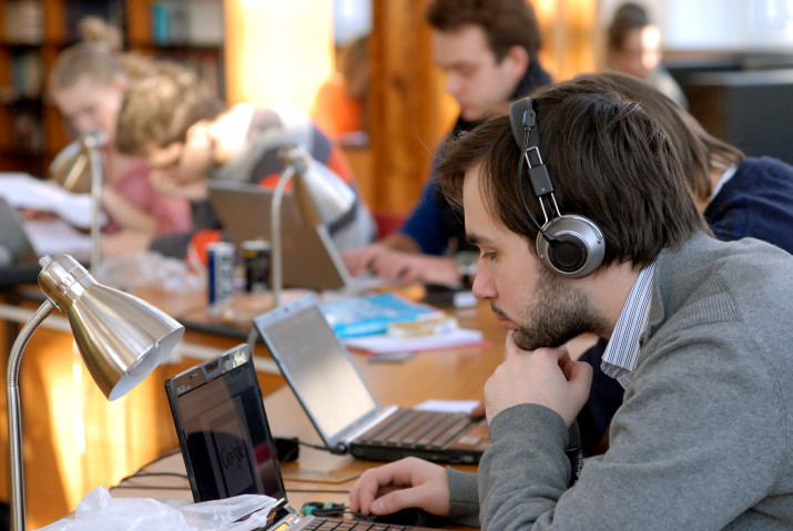 Student w słuchawkach pochylony nad laptopem