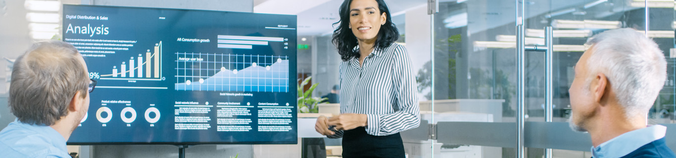 kobieta w biurze prezentująca wykresy analiz na ekranie przed dwójką mężczyzn zdjęcie