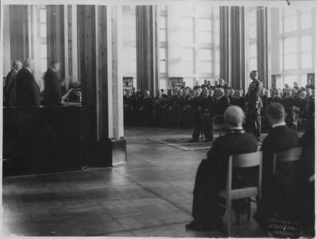 Uroczystość otwarcia biblioteki Wyższej Szkoły Handlowej. Przemawia minister Sławomir Czerwiński, widoczny m.in. prezydent RP Ignacy Mościcki. Za prezydentem stoi jego adiutant kpt. Zygmunt Gużewski. 1930 rok. Źródło: NAC