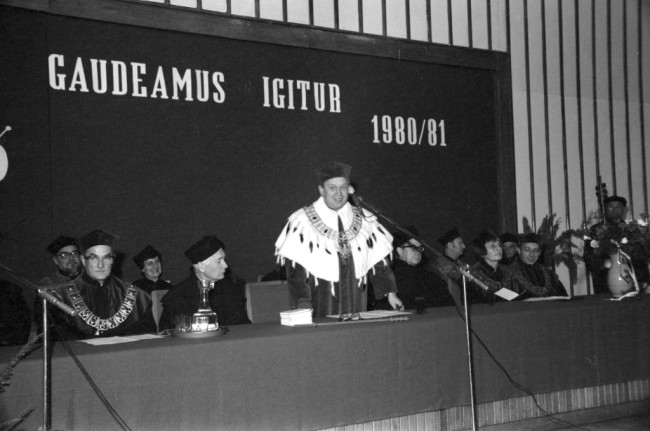 Inauguracja roku akademickiego 1980/1981  Przemawia JM Rektor prof. Stanisław Nowacki. W pierwszym rzędzie od lewej profesorowie: Witold Sierpiński – prorektor, Kazimierz Secomski – członek rzeczywisty PAN, Wiesław Sadowski - członek korespondent PAN, Barbara Prandecka – prorektor, Wojciech Wrzosek – prorektor. W drugim rzędzie od lewej profesorowie: Leszek Gilejko – dziekan Wydziału Ekonomiczno-Społecznego, Alicja Sajkiewicz – przedstawicielka – Wydziału Ekonomiczno-Społecznego