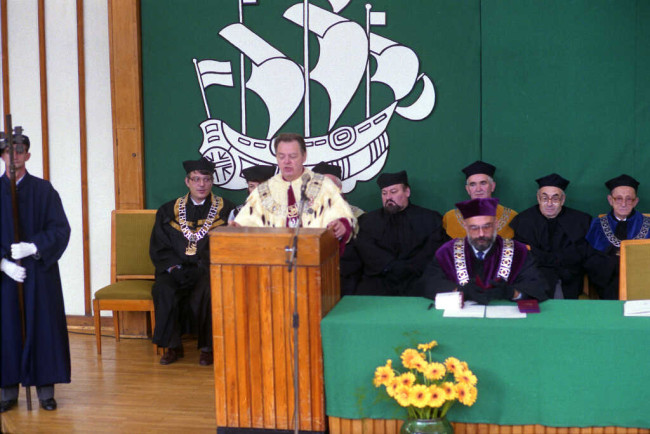 Inauguracja roku akademickiego 1992/1993. Przemawia rektor prof. Aleksander Müller. W pierwszym rzędzie siedzi prof. Marek Rocki – prorektor. W drugim rzędzie od lewej profesorowie: Tomasz Szapiro – dziekan Studium Dyplomowego, Władysław Szymański – przedstawiciel Wydziału Ekonomiki Produkcji, Janusz Kaliński – dziekan Wydziału Ekonomiczno-Społecznego, Zbigniew Landau – przedstawiciel Wydziału Ekonomiczno-Społecznego, Wiesław Flakiewicz – dziekan Wydziału Finansów i Statystyki