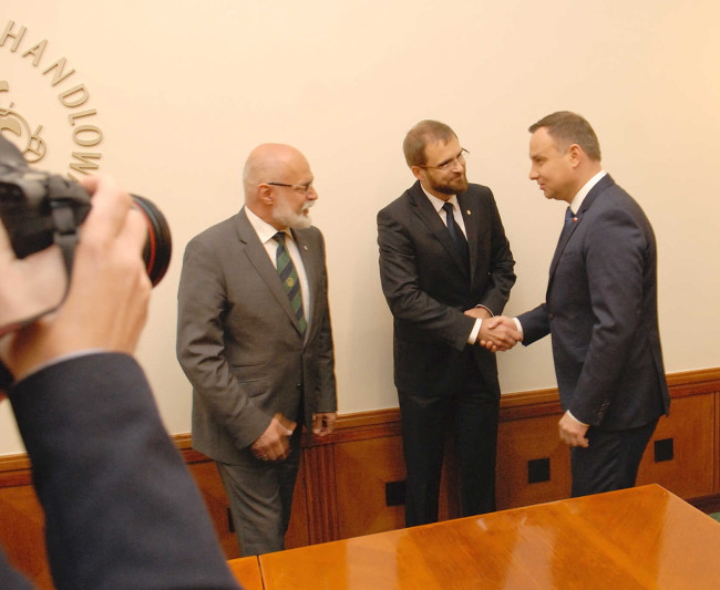 Powitanie Prezydenta RP Andrzeja Dudy w Sali Senatu. Na zdjęciu prezydent RP AndrzPrezydent RP Andrzej Duda wpisuje się do księgi pamiątkowej ej Duda, Kanclerz SGH dr Marcin Dąbrowski, rektor prof. Marek Rocki