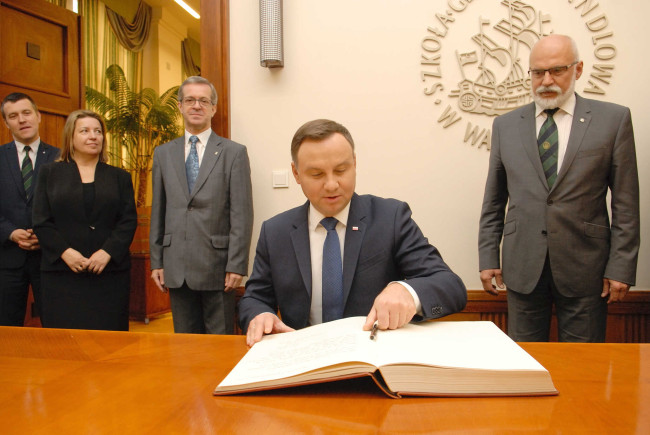 Prezydent RP Andrzej Duda wpisuje się do księgi pamiątkowej