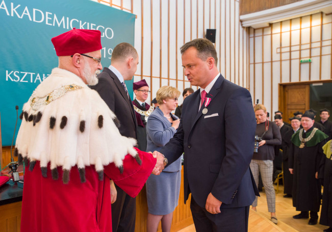 Inauguracja roku akademickiego 2018/2019​,  mgr Maciej Rysiński odbiera Medal Srebrny za Długoletnią Służbę. Gratulacje składa rektor prof. Marek Rocki  