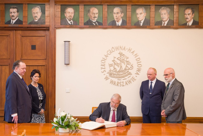 Prof. Paul H. Dembiński wpisuje się do księgi pamiątkowej SGH. Na zdjęciu: prof. Janusz Ostaszewski, małżonka prof. Paula H. Dembińskiego, prof. Paul H. Dembiński,  prof. Ryszard Bartkowiak, dziekan Kolegium Zarządzania i Finansów, rektor prof. Marek Rocki 