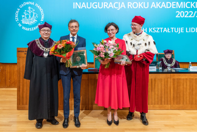 Grażyna Żebrowska i Jerzy Koźmiński trzymają medale i bukiet kwiatów. Obok laureatów stoją rektorzy
