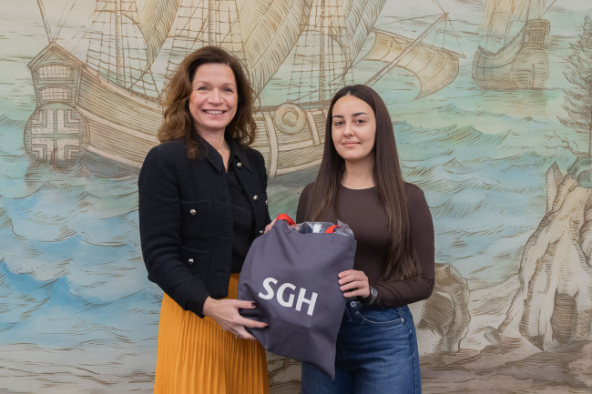 Prorektor ds. rozwoju wręcza pakiet upominków laureatce wyróżnienia w konkursie Hasło na dobry start.